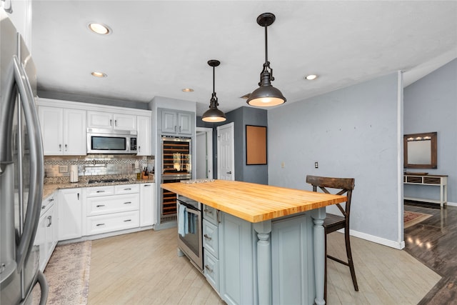 kitchen with white cabinets, a kitchen island, a kitchen breakfast bar, light hardwood / wood-style floors, and stainless steel appliances