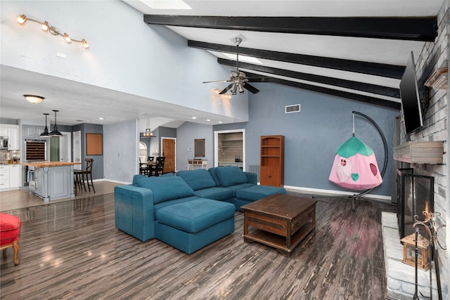 living room featuring vaulted ceiling with beams, hardwood / wood-style floors, a fireplace, and ceiling fan