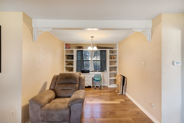 sitting room with light hardwood / wood-style floors, a chandelier, and a textured ceiling