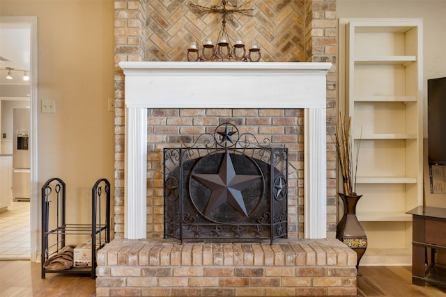 details with a brick fireplace, built in shelves, stainless steel fridge, and wood-type flooring