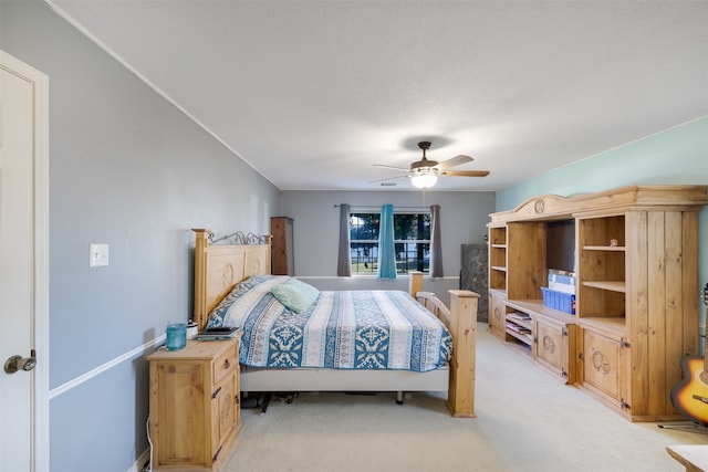 bedroom with ceiling fan, light carpet, and a textured ceiling