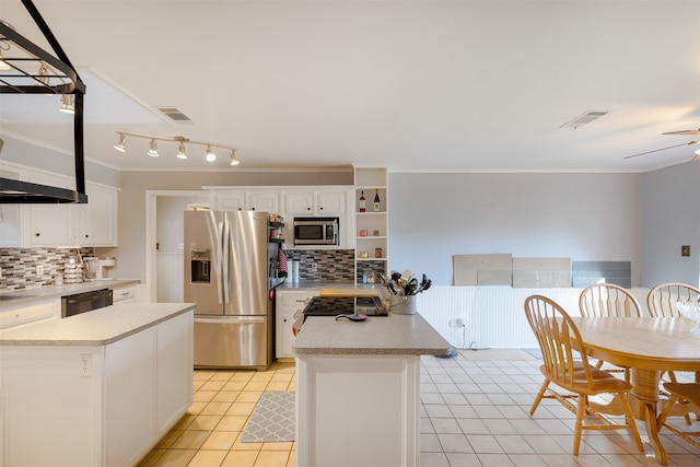 kitchen with appliances with stainless steel finishes, light tile patterned floors, backsplash, a kitchen island, and white cabinetry