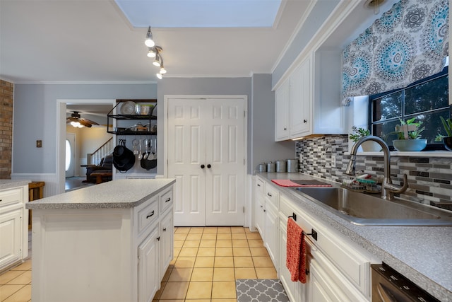 kitchen featuring light tile patterned floors, sink, dishwasher, a kitchen island, and white cabinets