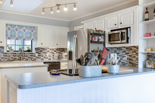 kitchen featuring appliances with stainless steel finishes, sink, white cabinets, ornamental molding, and tasteful backsplash