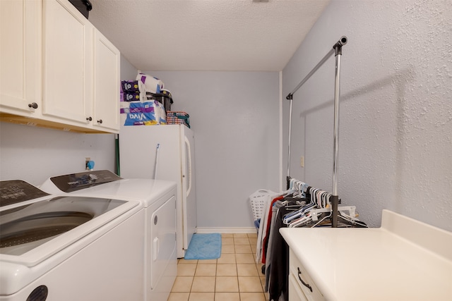 laundry area with cabinets, light tile patterned floors, a textured ceiling, and washing machine and clothes dryer