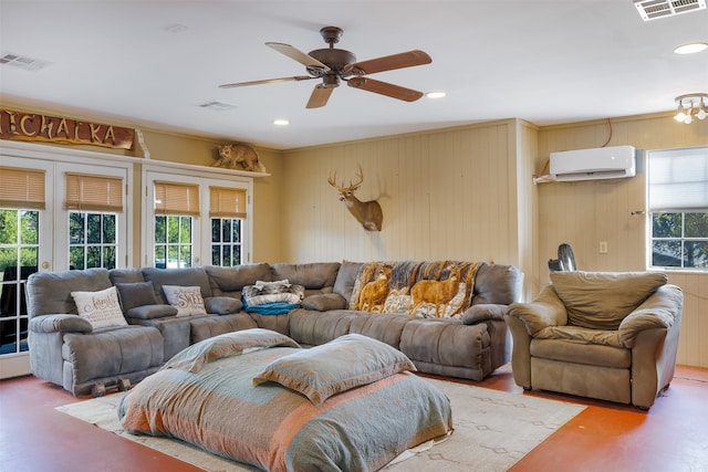 living room with a healthy amount of sunlight, wood walls, a wall mounted AC, and ceiling fan