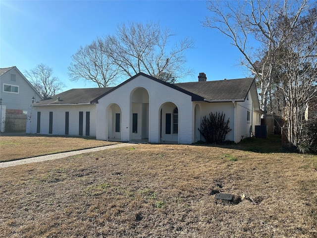 view of front of house with central AC, a front lawn, a chimney, and brick siding