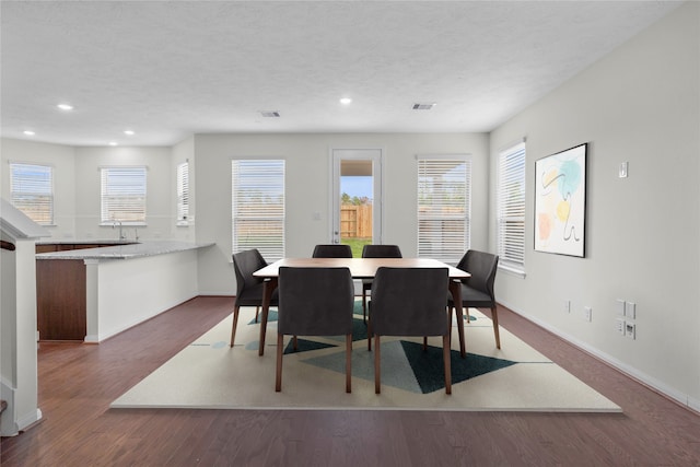 dining area with baseboards, a textured ceiling, wood finished floors, and a healthy amount of sunlight