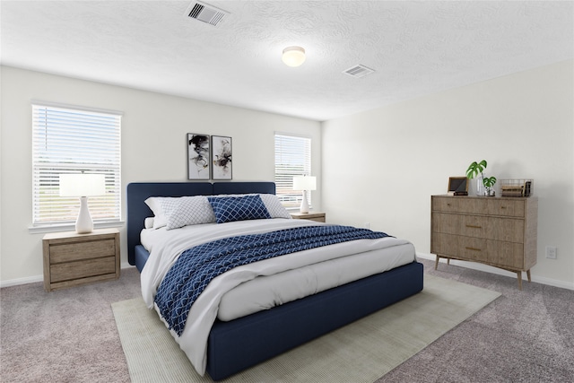 bedroom with light colored carpet and a textured ceiling