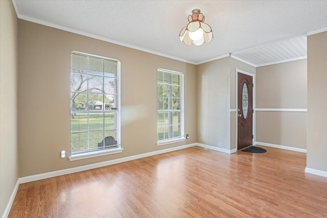 foyer with a textured ceiling, light hardwood / wood-style flooring, and ornamental molding