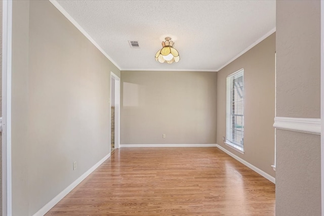 spare room with light hardwood / wood-style floors, ornamental molding, and a textured ceiling