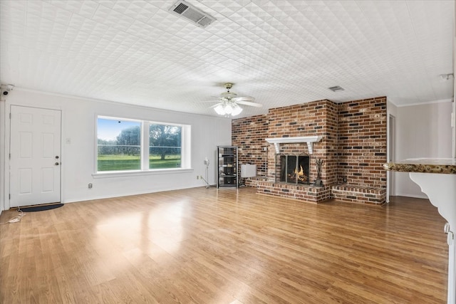 unfurnished living room with ornamental molding, a brick fireplace, hardwood / wood-style flooring, and ceiling fan