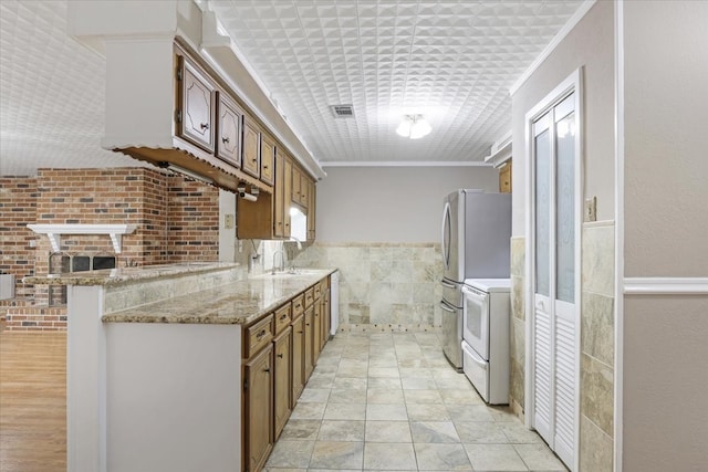 kitchen with kitchen peninsula, stainless steel fridge, electric range, ornamental molding, and light stone counters