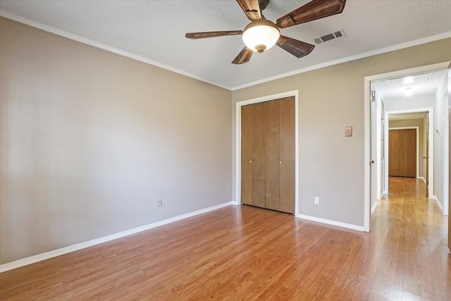 unfurnished bedroom with light hardwood / wood-style floors, a closet, a textured ceiling, and ceiling fan