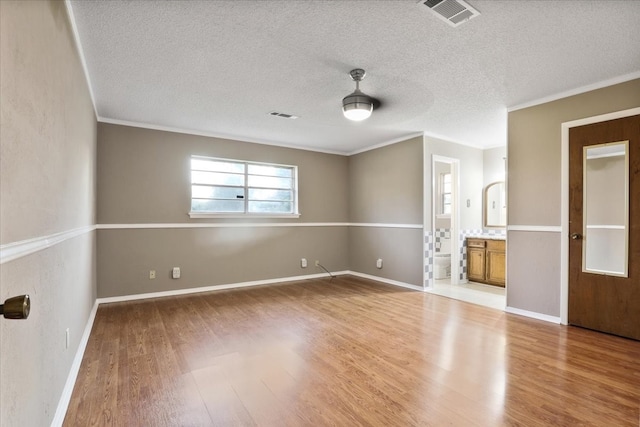 spare room with crown molding, wood-type flooring, and a textured ceiling