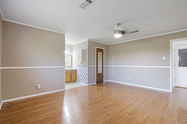 empty room with light hardwood / wood-style flooring, a textured ceiling, ceiling fan, and crown molding