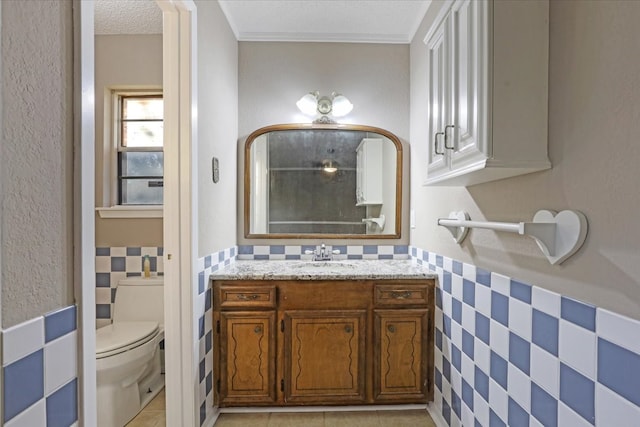 bathroom with toilet, vanity, tile walls, and tile patterned flooring