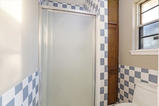 bathroom with toilet, walk in shower, and tile walls