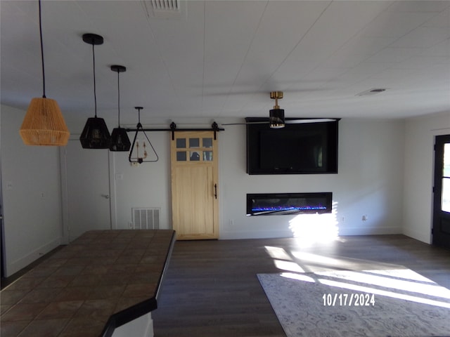 interior space featuring a barn door, decorative light fixtures, and dark hardwood / wood-style flooring