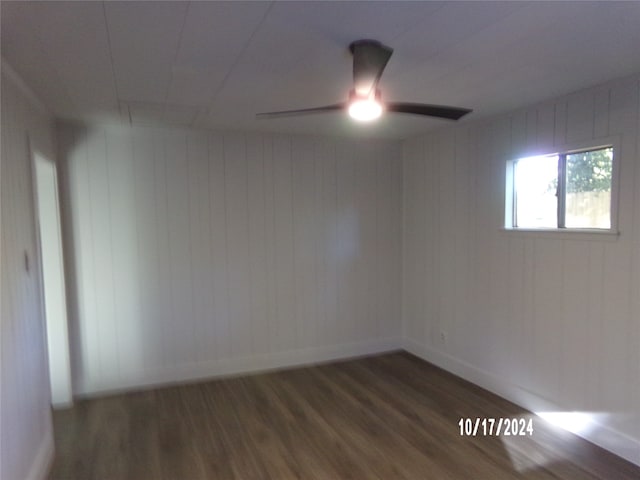 spare room with ceiling fan, wood walls, and dark hardwood / wood-style flooring