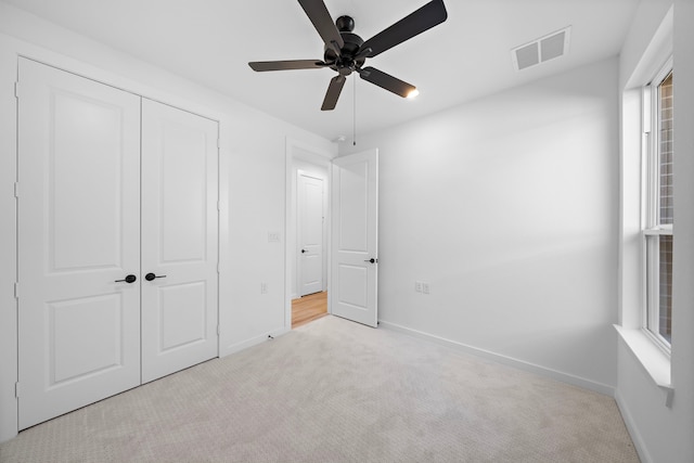 unfurnished bedroom with light carpet, ceiling fan, and a closet