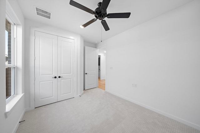 unfurnished bedroom featuring light carpet, ceiling fan, and a closet