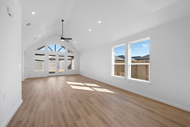 unfurnished living room featuring plenty of natural light, high vaulted ceiling, light hardwood / wood-style floors, and french doors