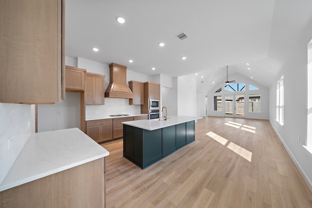 kitchen with premium range hood, appliances with stainless steel finishes, light hardwood / wood-style flooring, and a spacious island