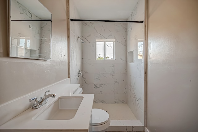 bathroom featuring toilet, vanity, and a tile shower