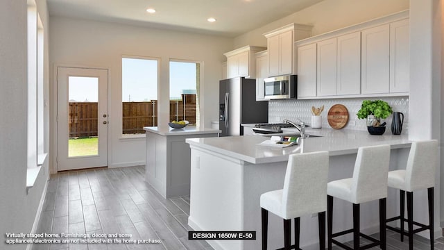 kitchen with white cabinetry, light hardwood / wood-style floors, appliances with stainless steel finishes, and kitchen peninsula