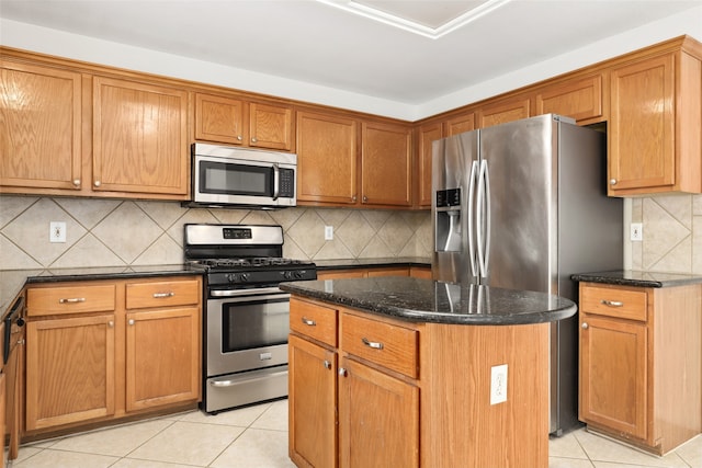 kitchen with a center island, stainless steel appliances, dark stone countertops, decorative backsplash, and light tile patterned floors