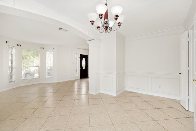 unfurnished room with ornate columns, light tile patterned floors, ornamental molding, and an inviting chandelier