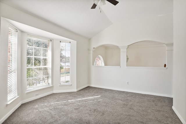 carpeted spare room with decorative columns, ceiling fan, and lofted ceiling