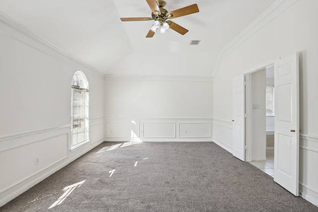 carpeted spare room featuring ceiling fan, ornamental molding, and vaulted ceiling