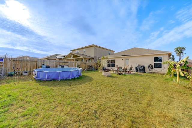 rear view of property featuring a patio area, a fenced in pool, and a lawn