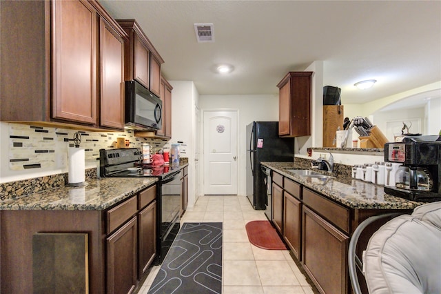 kitchen with sink, black appliances, light tile patterned floors, and dark stone counters