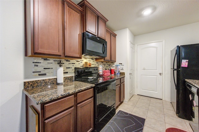 kitchen featuring tasteful backsplash, light tile patterned floors, a textured ceiling, dark stone countertops, and black appliances