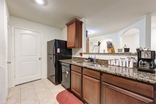 kitchen featuring dark stone countertops, black appliances, sink, and light tile patterned floors