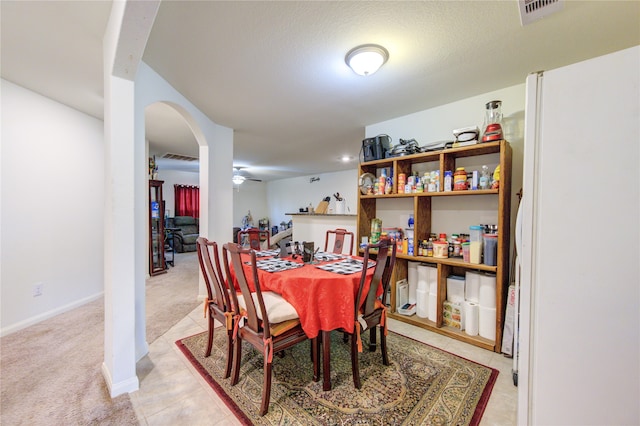 dining room featuring ceiling fan, a textured ceiling, and light colored carpet