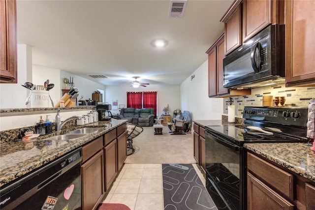 kitchen featuring light colored carpet, black appliances, sink, and dark stone counters