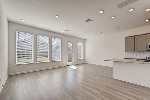 interior space with sink, light stone countertops, light hardwood / wood-style flooring, and decorative backsplash