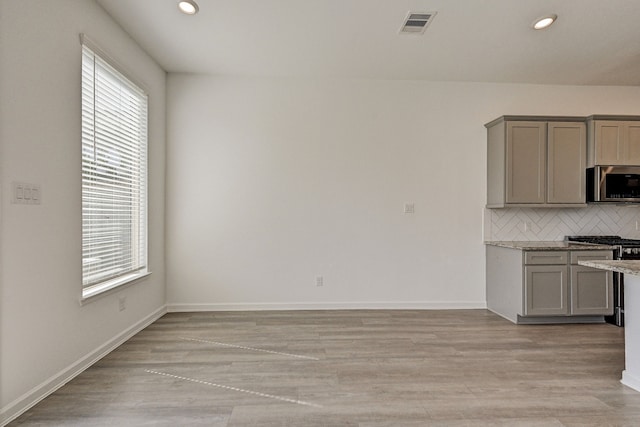 kitchen featuring appliances with stainless steel finishes, light stone counters, backsplash, and plenty of natural light