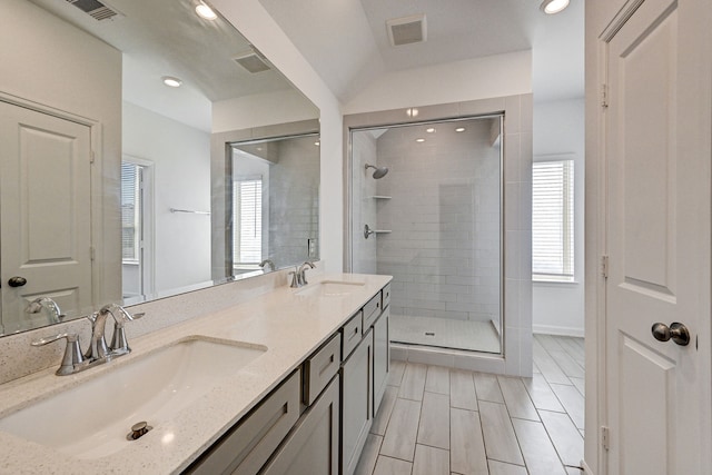 bathroom featuring a shower with door, vaulted ceiling, and vanity