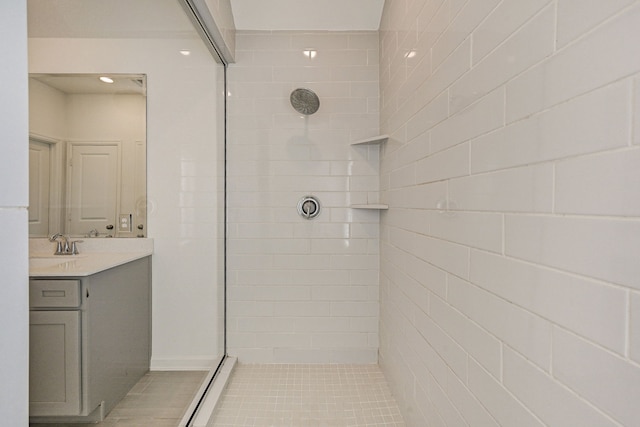 bathroom featuring a tile shower, vanity, and tile patterned flooring