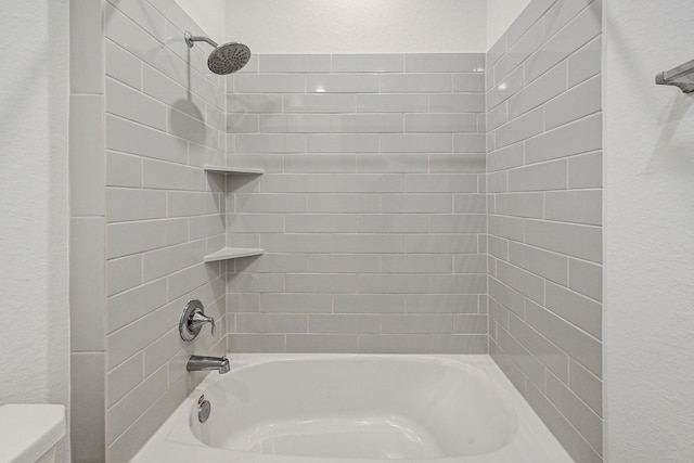 bathroom with toilet and tiled shower / bath combo