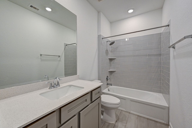 full bathroom featuring tiled shower / bath, vanity, and toilet