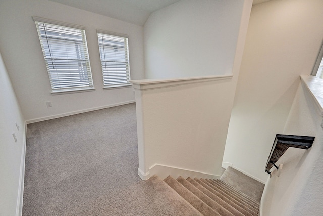 stairway featuring a large fireplace, carpet, and vaulted ceiling