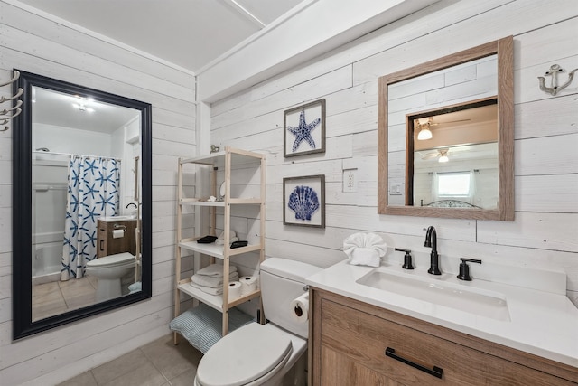 bathroom with vanity, toilet, wooden walls, and tile patterned flooring