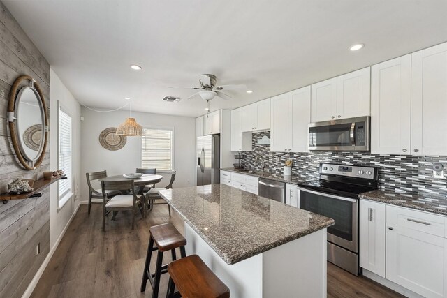 kitchen featuring visible vents, a center island, tasteful backsplash, appliances with stainless steel finishes, and dark wood-style flooring