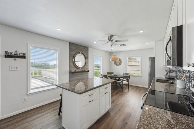 kitchen featuring a ceiling fan, a sink, stainless steel appliances, white cabinets, and baseboards